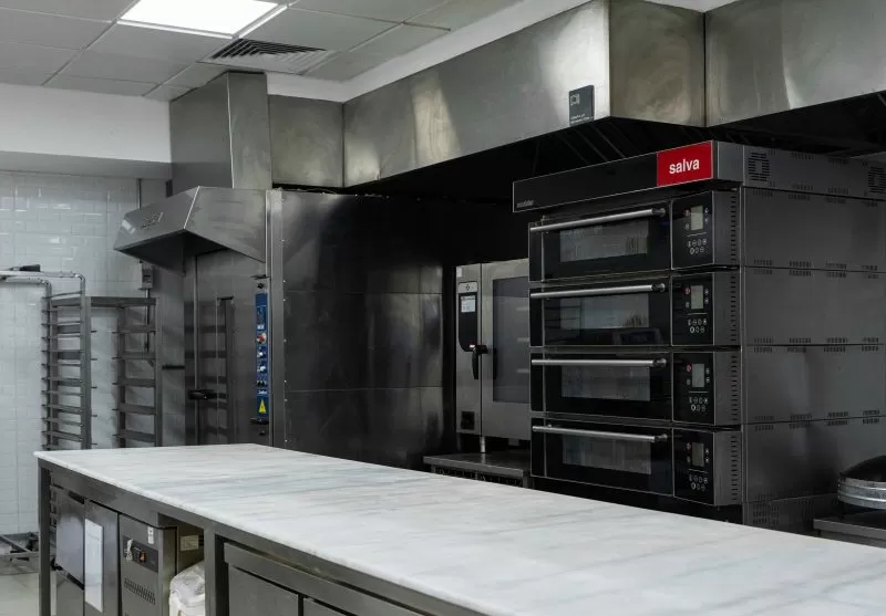 Deck ovens and combi ovens beside a marble work counter in the Plum kitchen